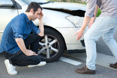 2 men crouch by a damaged car after a learner driver car accident