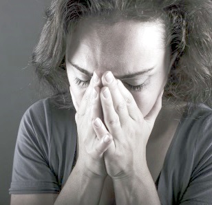 A woman places her head in her hands.