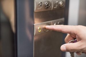 A close up shot of a hand pressing the emergency button in a lift.