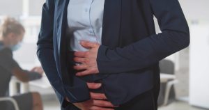 A woman is holding her stomach in pain.