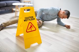 A man slipping next to a wet floor sign